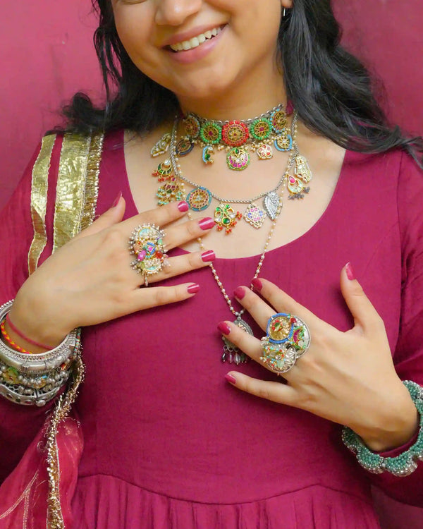 Woman wearing colorful jewelry including a necklace, ring, and bangles against a red background