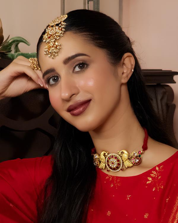 Woman wearing gold jewelry including a headband, necklace, and earrings.