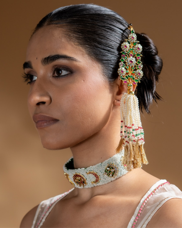 Woman wearing a decorative headpiece and necklace against a brown background