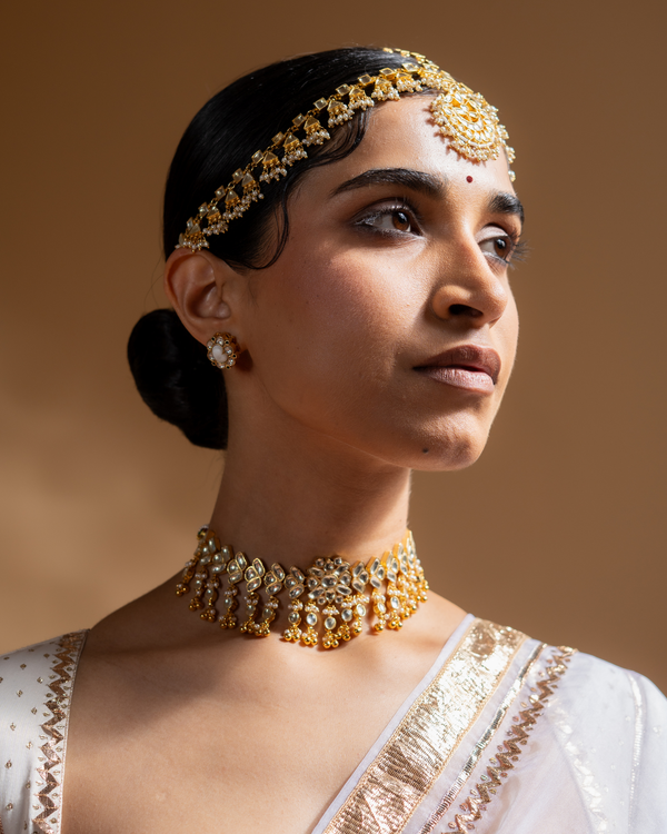 Woman wearing gold jewelry against a warm brown background