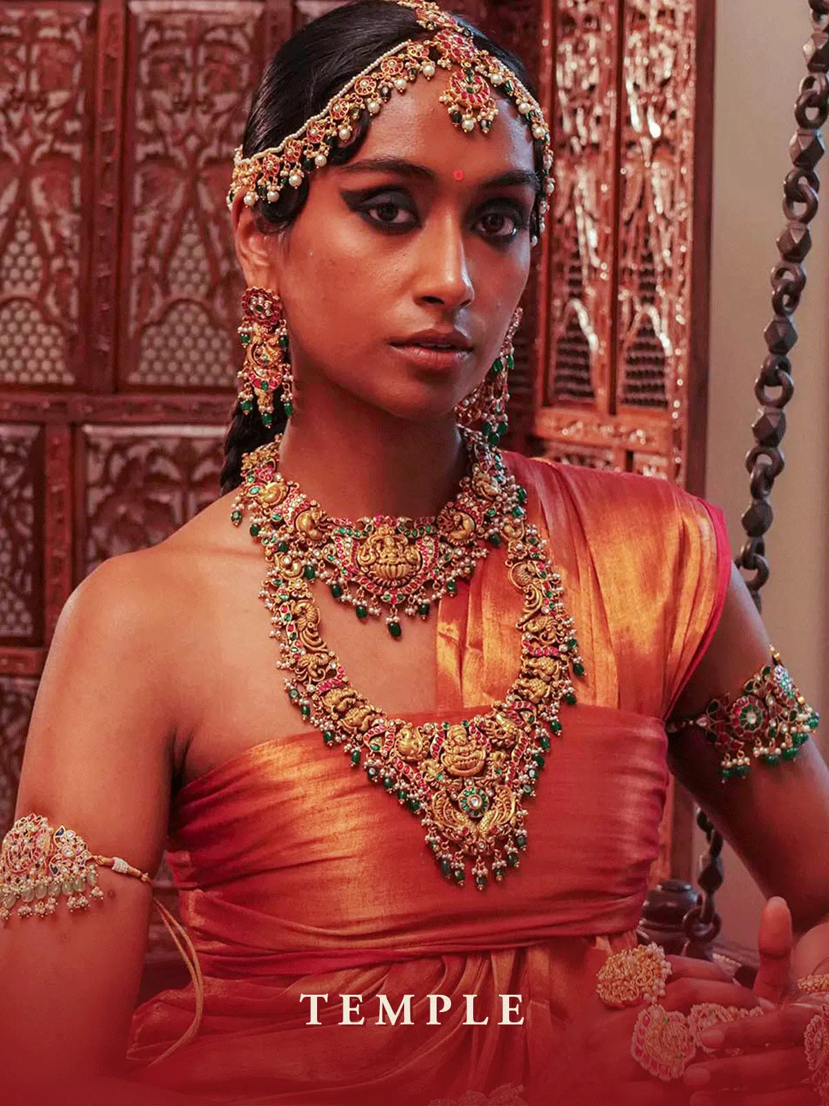 Model wearing traditional Indian temple jewellery with an ornate gold necklace, earrings and headpiece by Mortantra